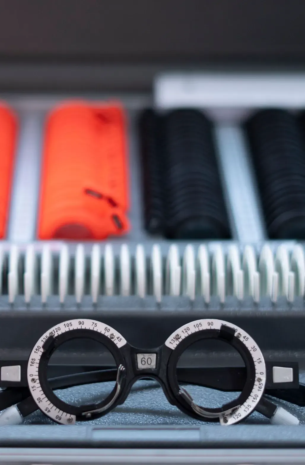 A trial frame in front of rows of test lenses in an optician's case